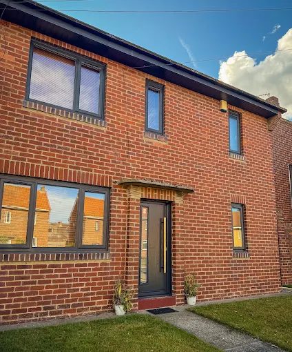 Front of a red-brick house with anthracite grey windows and a matching anthracite front door
