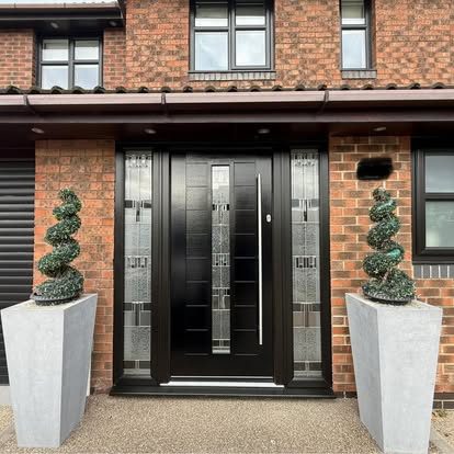 Front of a red-brick house with a black composite front door and decorative glazed side panels
