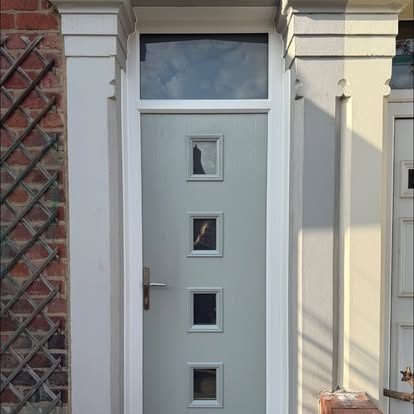 Light grey composite front door with four small square glass panels and a glazed toplight