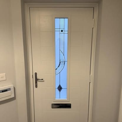 White composite door from inside the hallway, with a tall panel of decorative glass