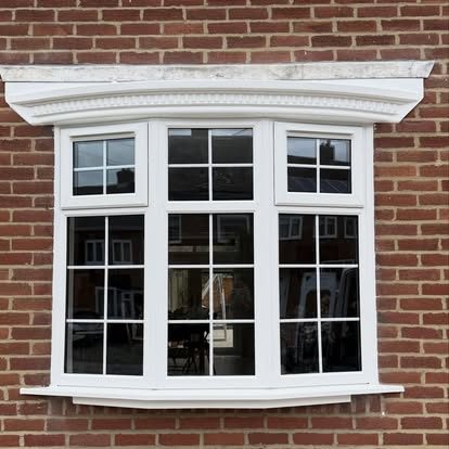 White uPVC casement bay window with Georgian bars set into red brick under a decorative header
